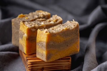 Pieces of natural handmade soap on a wooden soap dish and the dark background