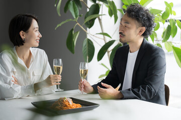Man and woman staring at each other eating in a restaurant, holding wine glasses, date or couple