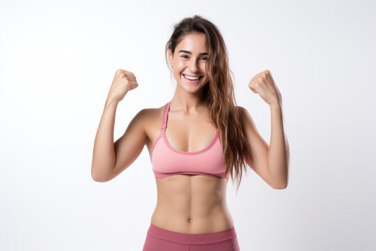 Portrait of a smiling sportswoman in pink sportswear showing her biceps isolated on a white background and Looking at the camera.