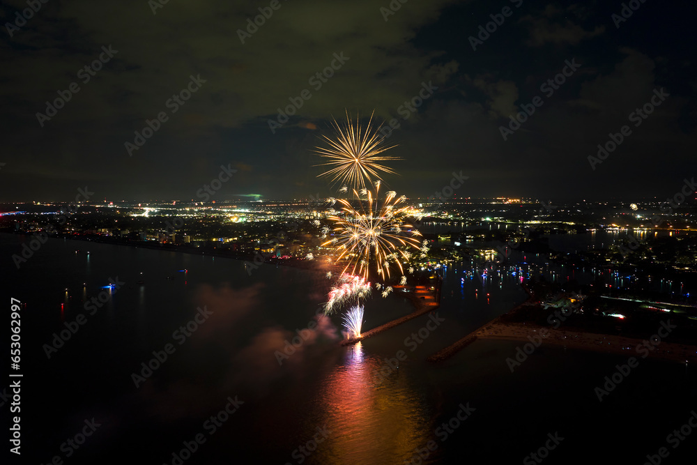 Wall mural Aerial view of bright fireworks exploding with colorful lights over sea shore on US Independence day holiday - Wall murals