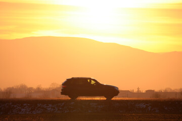 SUV car driving fast on intercity road at sunset. Highway traffic in evening
