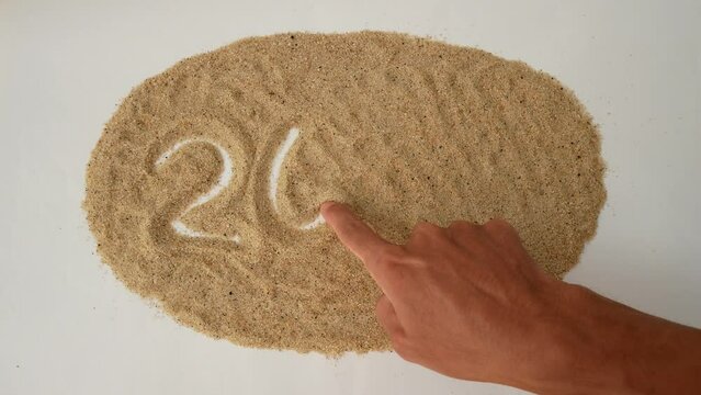A hand is writing on the sand 2024