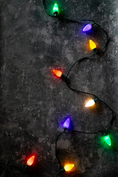 String of glowing holiday lights on a concrete gray background