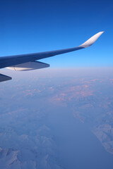 An airplane wing and a view on a North Pole snowy landscape while flying the polar route.