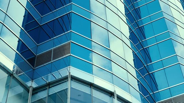 Abstract modern business architecture. Walls made of glass and steel with reflections of buildings and blue sky.	