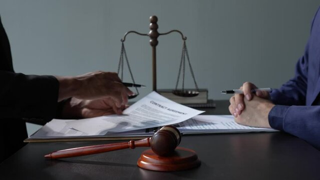 The lawyer working with a client discussing contract paper, a Business lawyer working about legal legislation in the courtroom to help their customer.	
