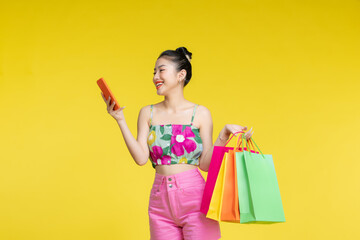 young woman holding shopping bags and smart phone - 653093512