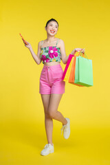 Young Asian woman holding mobile phone and shopping bags, smiling face, cheerful figure