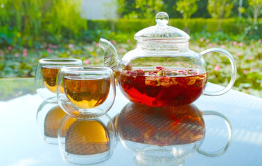 Cups of hot fragrant rose tea being served on garden table