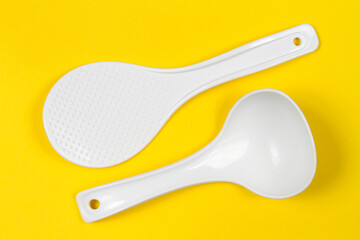 Plastic spoon and spatula for use with non-stick cookware. Set of plastic dishes on a yellow background.