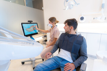 Dentist using modern technology to explain procedure to a man - obrazy, fototapety, plakaty