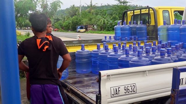 Workers loading trucks by hand with purified drinking water ready to supply the people of the Philippines with sae clean drinking water. 