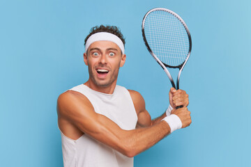 Tennis player with tennis racket in his hands on blue background, happy guy won the set, sports life concept, copy space
