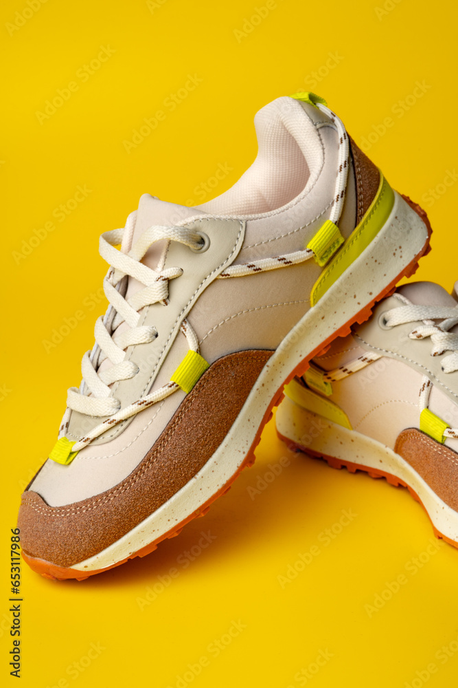 Poster Beige sport running shoes on yellow studio background