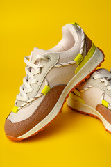 Beige sport running shoes on yellow studio background