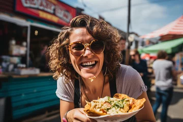 Tuinposter Beautiful young woman with curly hair and sunglasses eating pizza in a street food market. © Nerea