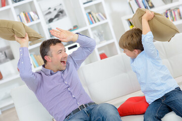 Obraz premium Father and son play fighting with cushions