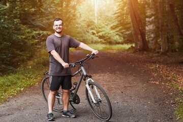 Naklejka premium Outdoor Adventure. Man Enjoying Mountain Biking in Natural Landscape. Countryside Cycling. Young Male Biker on a Mountain Bike