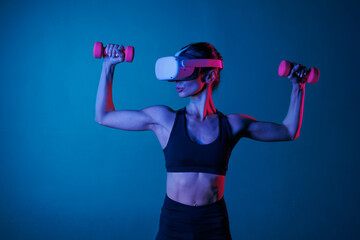 athletic girl doing sports online in VR glasses on a dark background, online sports training
