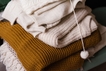 Stack of knitted blankets and sweaters in a cozy winter bedroom