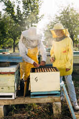 Man is teaching young woman how to smoke beehive.