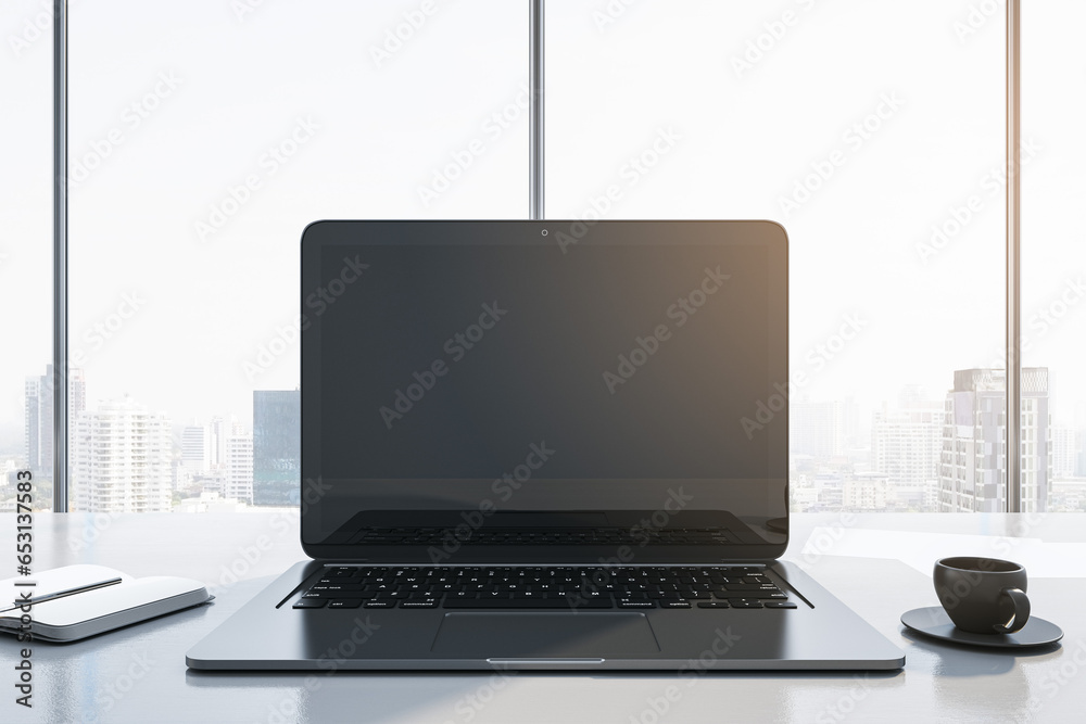 Poster Close up of modern workplace with empty mock up laptop screen, supplies, coffee cup and panoramic window with city view in the background. 3D Rendering.
