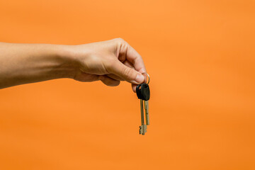 Man's hand holding keys isolated on orange background