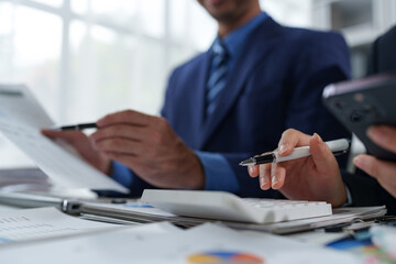 team work process Business team use calculator to calculate figures, business statistics, profit, cost analysis, growth rate graph document. data charts on the desk
