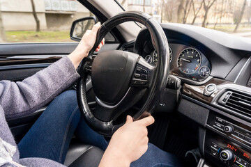 Women's hands holding steering wheel of the car. Driving