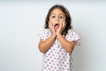 Stupefied beautiful kid girl wearing dress expresses excitement and thrill, keeps jaw dropped,...