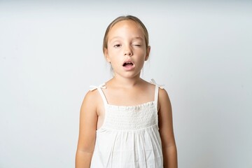 beautiful kid girl wearing white dress yawns with opened mouth stands. Daily morning routine