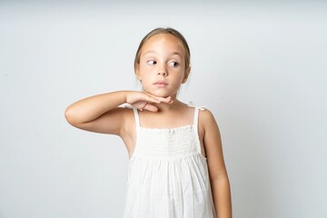 beautiful kid girl wearing white dress cutting throat with hand as knife, threaten aggression with...