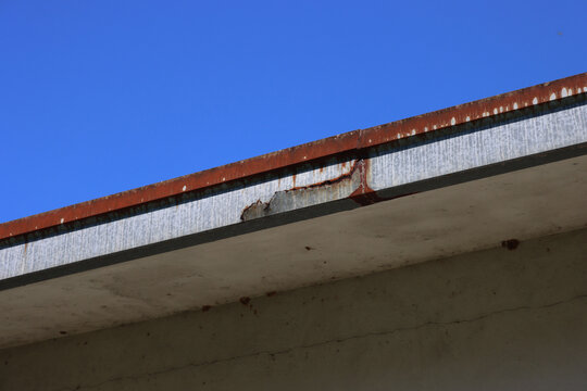 Damaged and rusty old metal rain gutter on old roof 