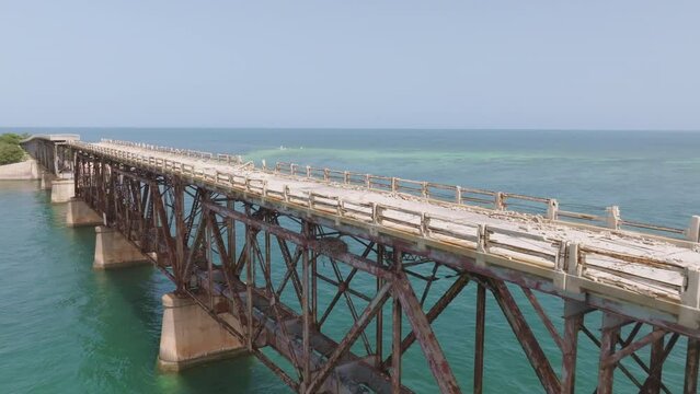 Aerial trucking pan along decrepit broken run down bridge in middle of ocean