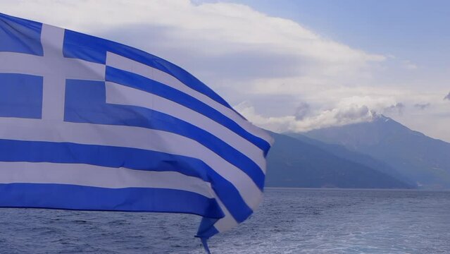 Slow-Motion Footage: Greek Flag on a sailing ship with Mount Athos and the blue sea in the background, Halkidiki Peninsula.