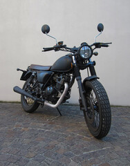 Obraz na płótnie Canvas Moto classica nera opaco con rifiniture argentate, griglia sul fanale e sella in pelle ricamata stile vintage