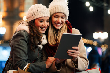 Women friends enjoy the night in shopping at Christmas. Sale, people digital tablet concept