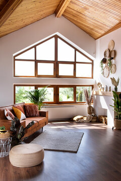 Modern living room with fireplace, sofa, wooden attic ceiling and big window