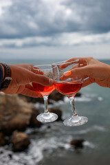 two glasses of pink champagne. Male and female hands hold glasses. romantic date on the background of the sea