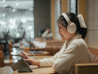 Asian teen girl using tablet watching online multimedia in coffee shop