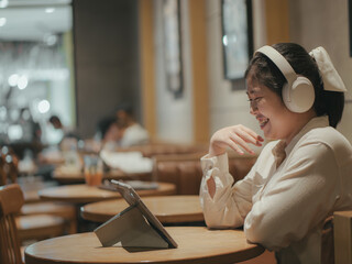 Asian teen girl using tablet watching online multimedia in coffee shop