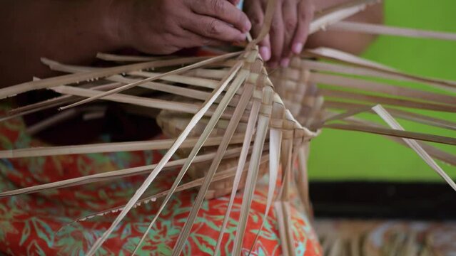 An Indonesian woman´s hand weaving an ancestral basket case from mangrove palm leaves . People is demonstrating weaving basket made from nipa palm. Weaving a traditional basket made from mangrove palm