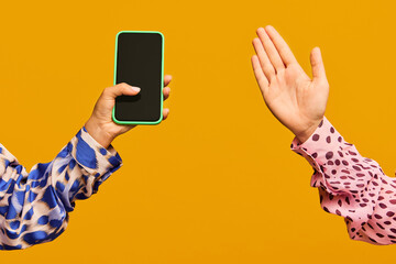 Poster. Two hands, female holding phone with blank screen, male showing palm isolated on orange color background.