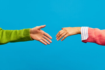 Poster. Two hands, female and male reaching out to each other for welcome handshake isolated on blue color background. - obrazy, fototapety, plakaty