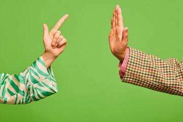 Poster. Two hands, female showing forefinger like critique, male demonstrate stop gesture isolated on green background.
