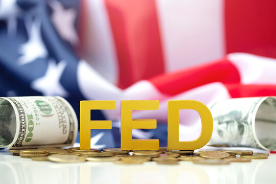 The Federal Reserve ( FED ) to control interest rates. Gold text FED on coins with USA flag background. American economy and business. Federal Reserve Bank Interest rates rise policy.