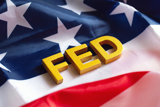 The Federal Reserve ( FED ) to control interest rates. Gold text FED on  USA flag background. American economy and business. Federal Reserve Bank Interest rates rise policy. World economy crisis.