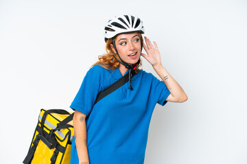 Young caucasian woman with thermal backpack isolated on white background listening to something by putting hand on the ear