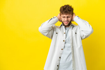 Young handsome caucasian man isolated on yellow background frustrated and covering ears