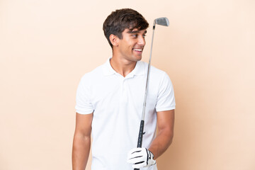 Young golfer player man isolated on ocher background looking side